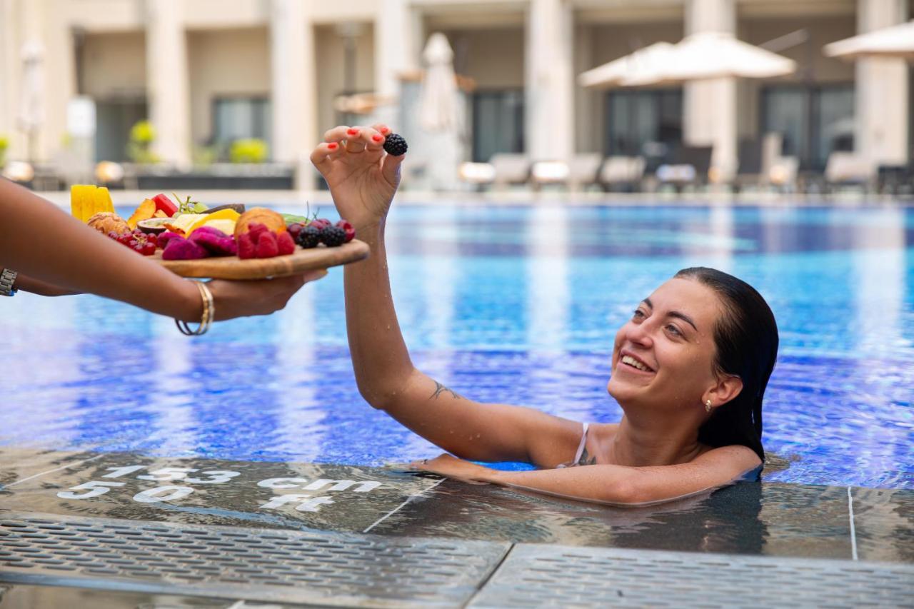 Triumph Luxury Hotel Kaherah Luaran gambar A woman being served fruit in a swimming pool